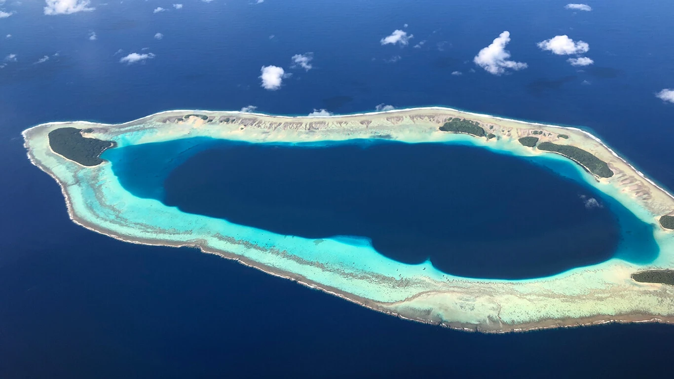 Bikini Atoll Atol koralowy otoczony turkusową wodą, z wyraźnie zaznaczoną laguną pośrodku oraz niewielkimi fragmentami lądu na obrzeżach.