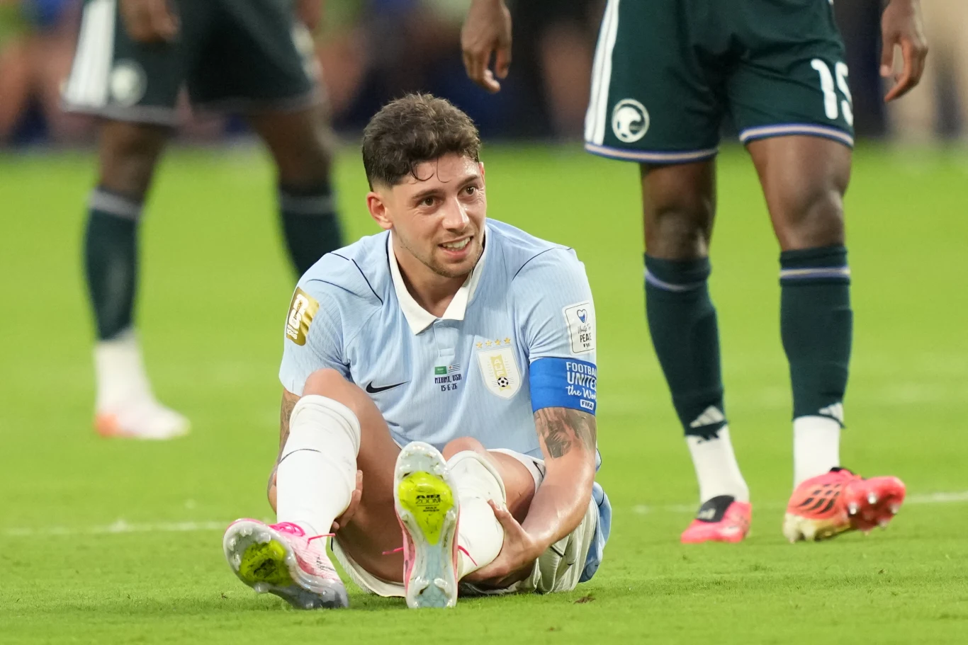 Fede Valverde jest kapitanem i największą gwiazdą Urugwaju na mistrzostwach świata 2026 Piłkarz w jasnoniebieskiej koszulce siedzi na murawie i trzyma się za nogę podczas meczu, wykazując oznaki bólu, wokół niego stoją zawodnicy drużyny przeciwnej.