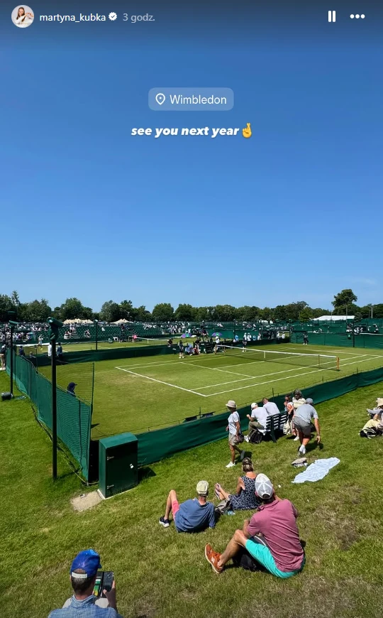 Martyna Kubka reaguje na brak przepustki do gry w eliminacjach Wimbledonu Kort tenisowy otoczony zielonym ogrodzeniem, wokół którego siedzą widzowie obserwujący trwający mecz pod bezchmurnym, niebieskim niebem.