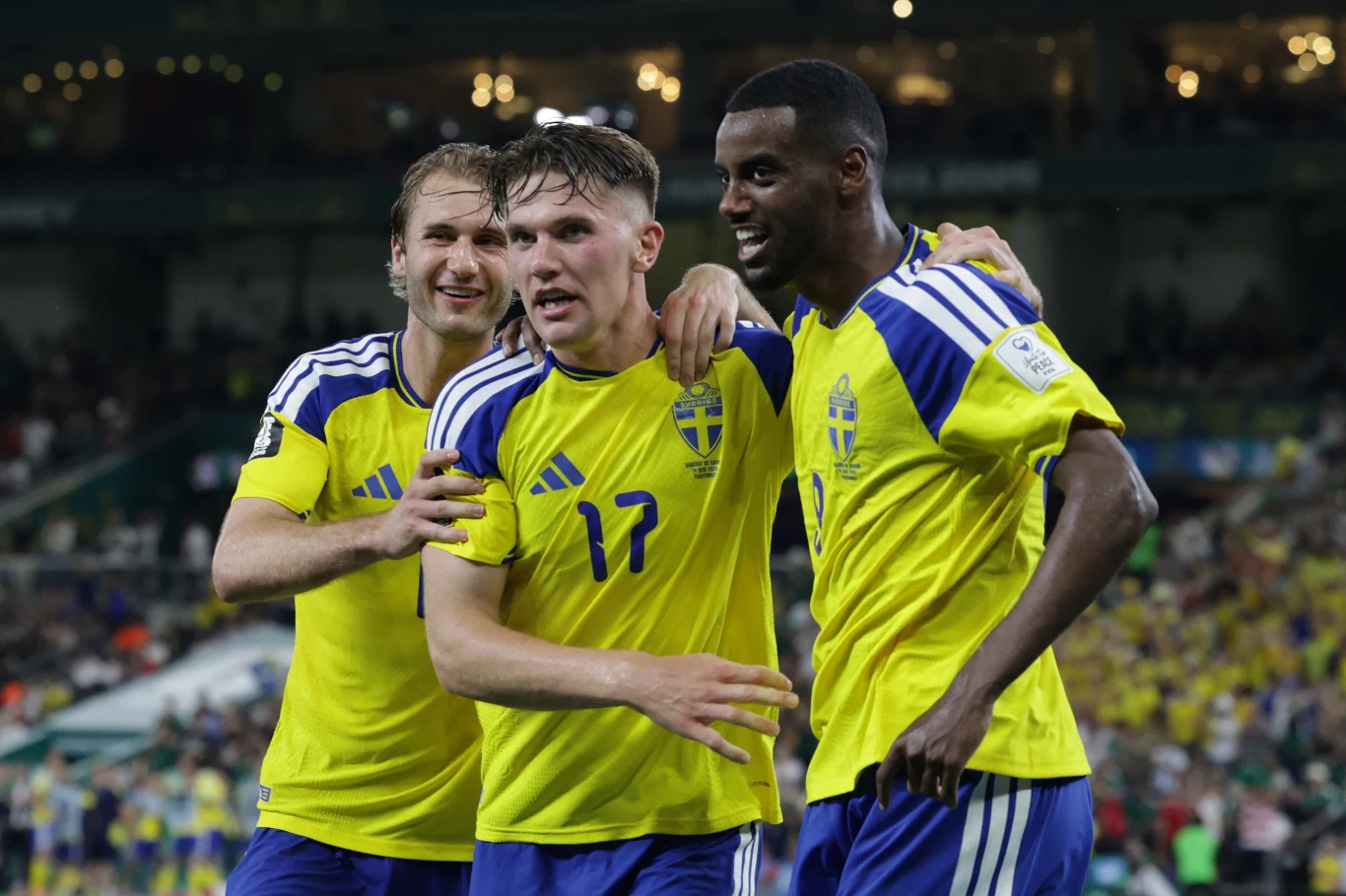 Reprezentacja Szwecji podczas mistrzostw świata Trzech piłkarzy w żółto-niebieskich strojach reprezentacji Szwecji celebrujących razem zdobycie gola na murawie stadionu.