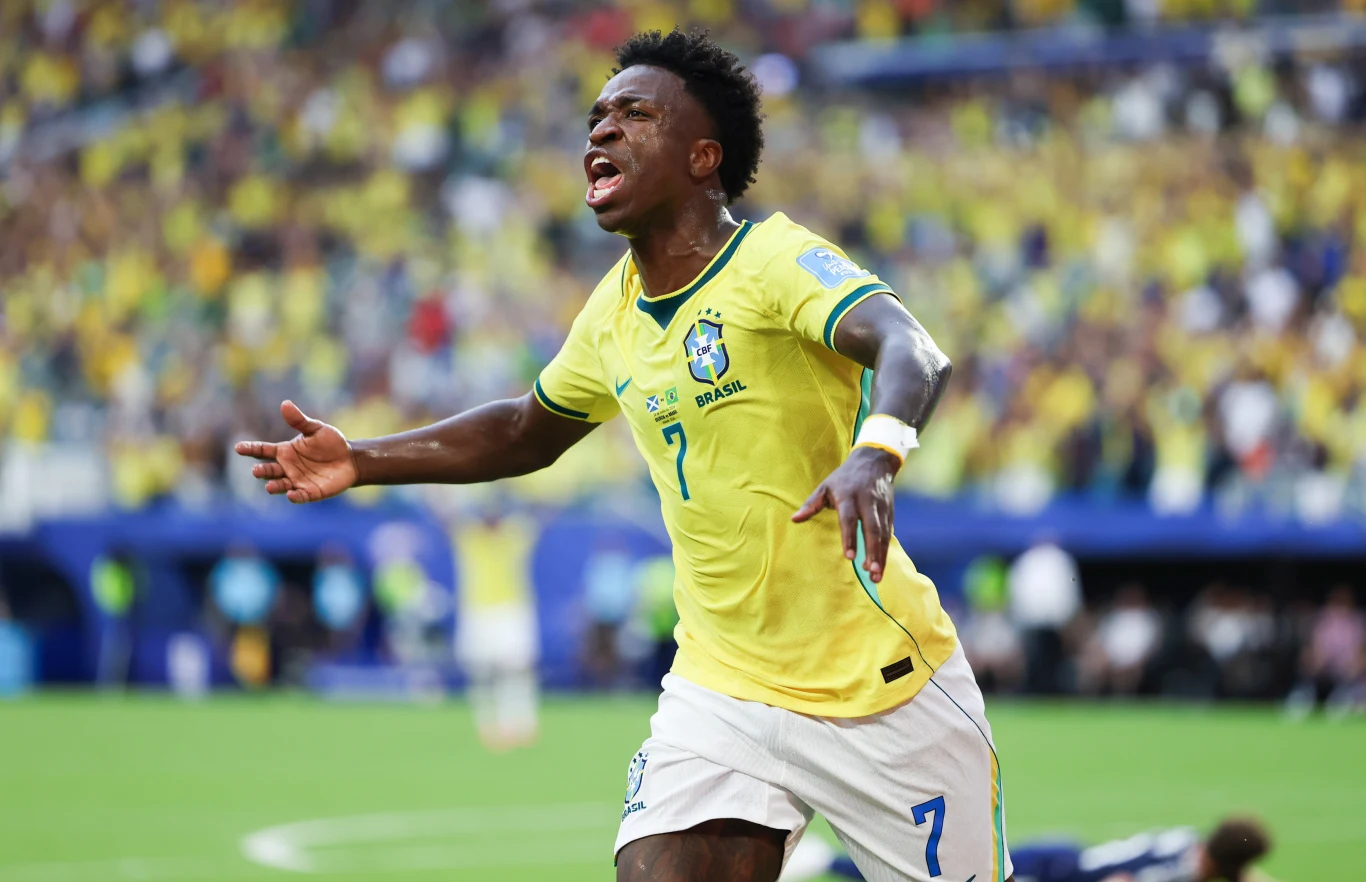 Vinicius Piłkarz w żółtej koszulce reprezentacji Brazylii z numerem 7 świętuje po zdobyciu bramki na stadionie wypełnionym kibicami.