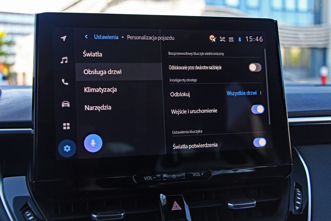 Dotykowy ekran systemu multimedialnego w samochodzie, wyświetlający ustawienia personalizacji pojazdu, w tym opcje zarządzania światłami, drzwiami i klimatyzacją.
