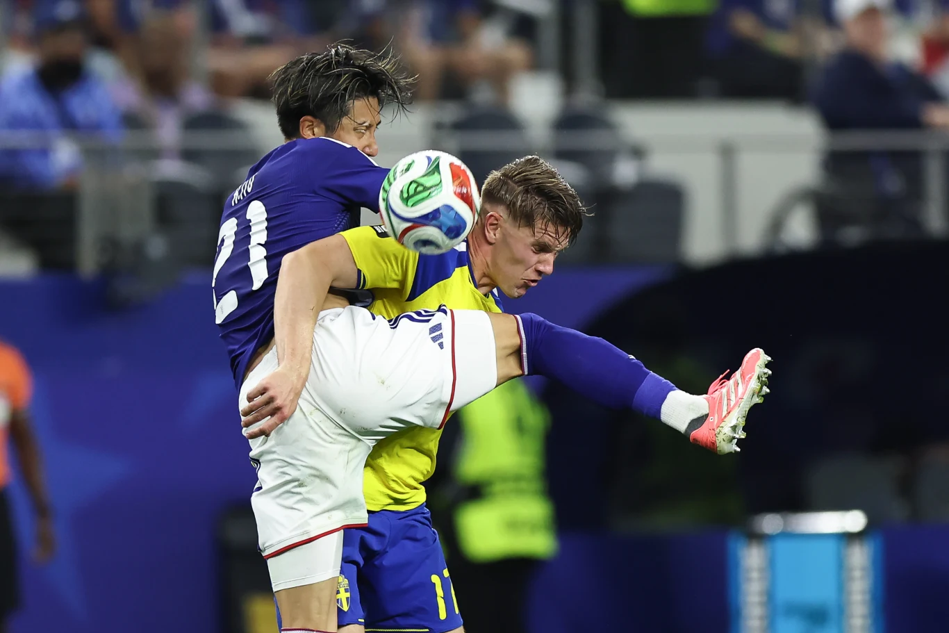 Kadr z meczu Japonia - Szwecja Piłkarze Japonii i Szwecji walczą o piłkę podczas meczu grupowego MŚ 2026, jeden podnosi wysoko nogę.