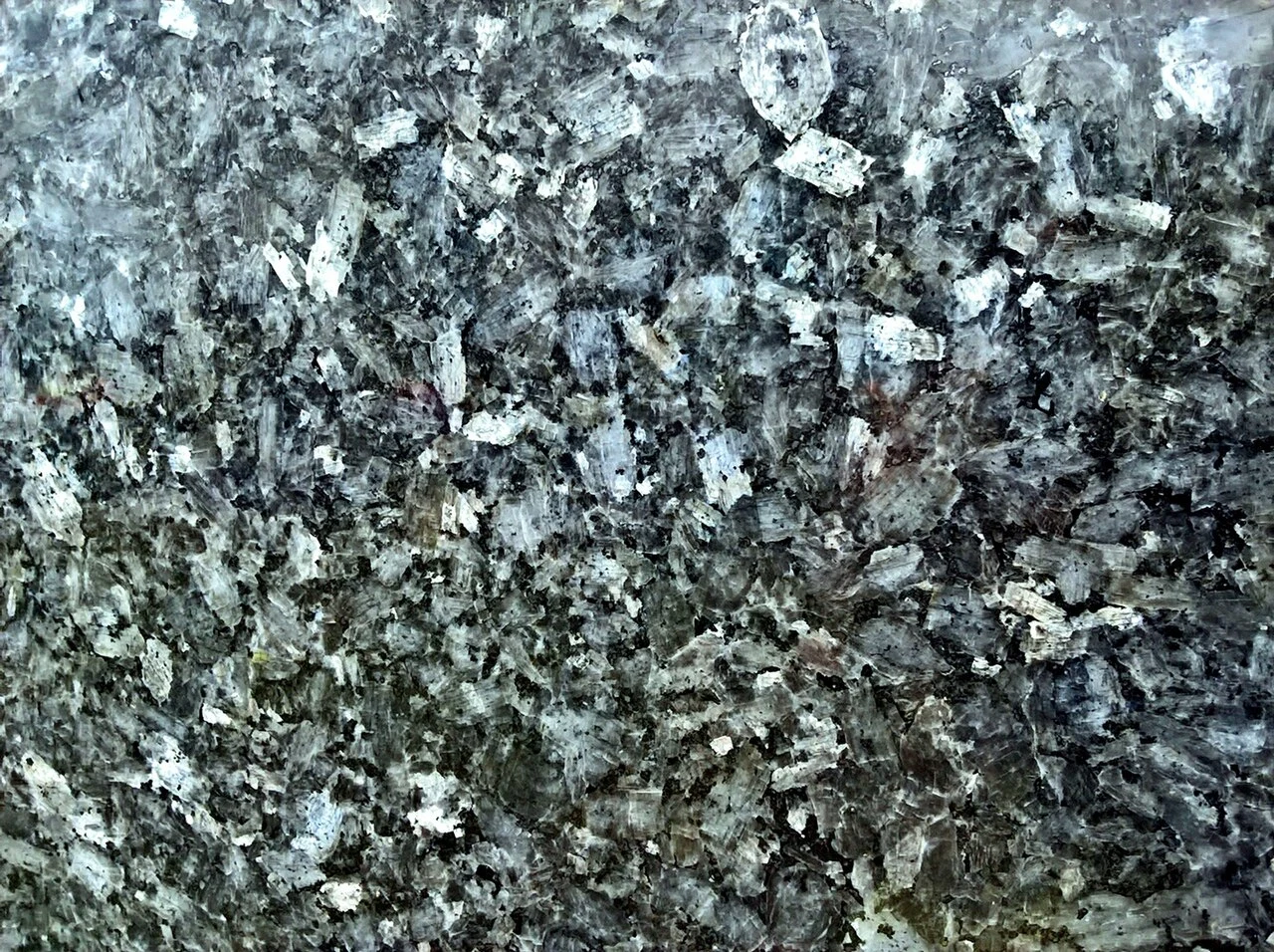 Szarosrebrzysta powierzchnia granitu z wyraźnymi, nieregularnymi kryształami minerałów oraz subtelnymi, kontrastującymi odcieniami bieli i czerni.