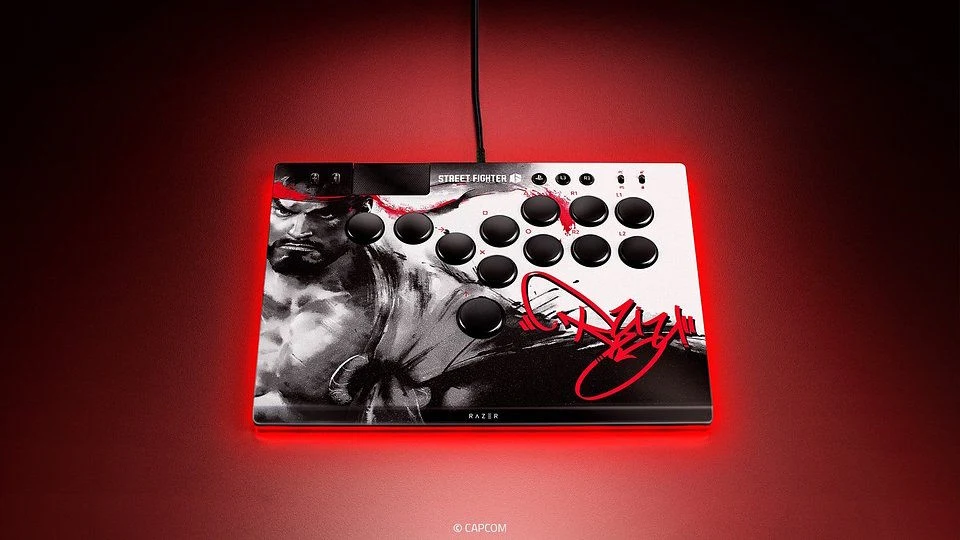 Kontroler arcade z podświetleniem LED, ozdobiony grafiką przedstawiającą postać z gry Street Fighter oraz dużym, czerwonym podpisem na białym tle.