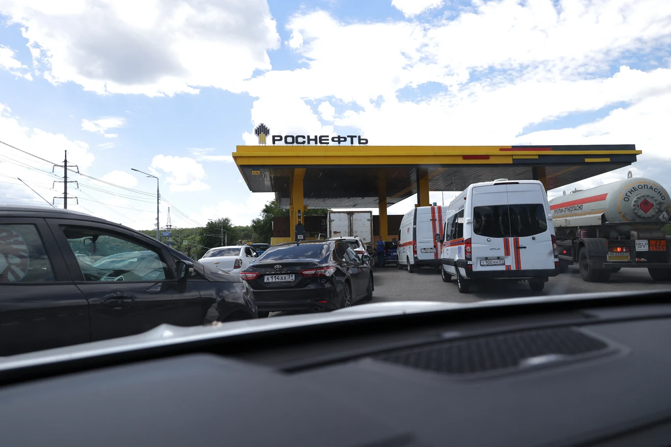 Na rosyjskich stacjach, na których paliwo jest dostęne, tworzą się kolejki Kolejka samochodów i ciężarówek na stacji paliw Rosnieft pod żółtym zadaszeniem, widok z auta.