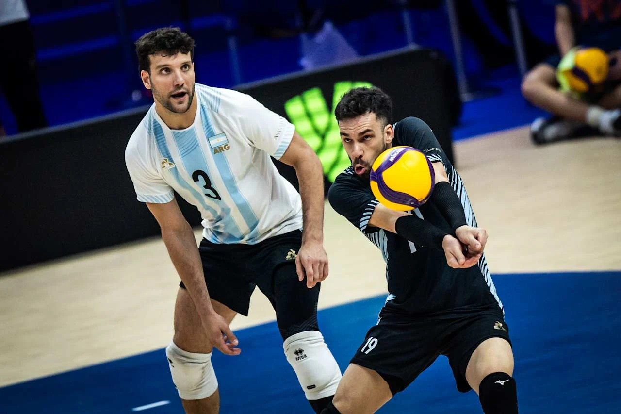 Siatkarze reprezentacji Argentyny Dwóch siatkarzy w dynamicznej akcji, jeden z nich przyjmuje piłkę sposobem dolnym, a drugi obserwuje sytuację, przygotowany do kolejnego ruchu.