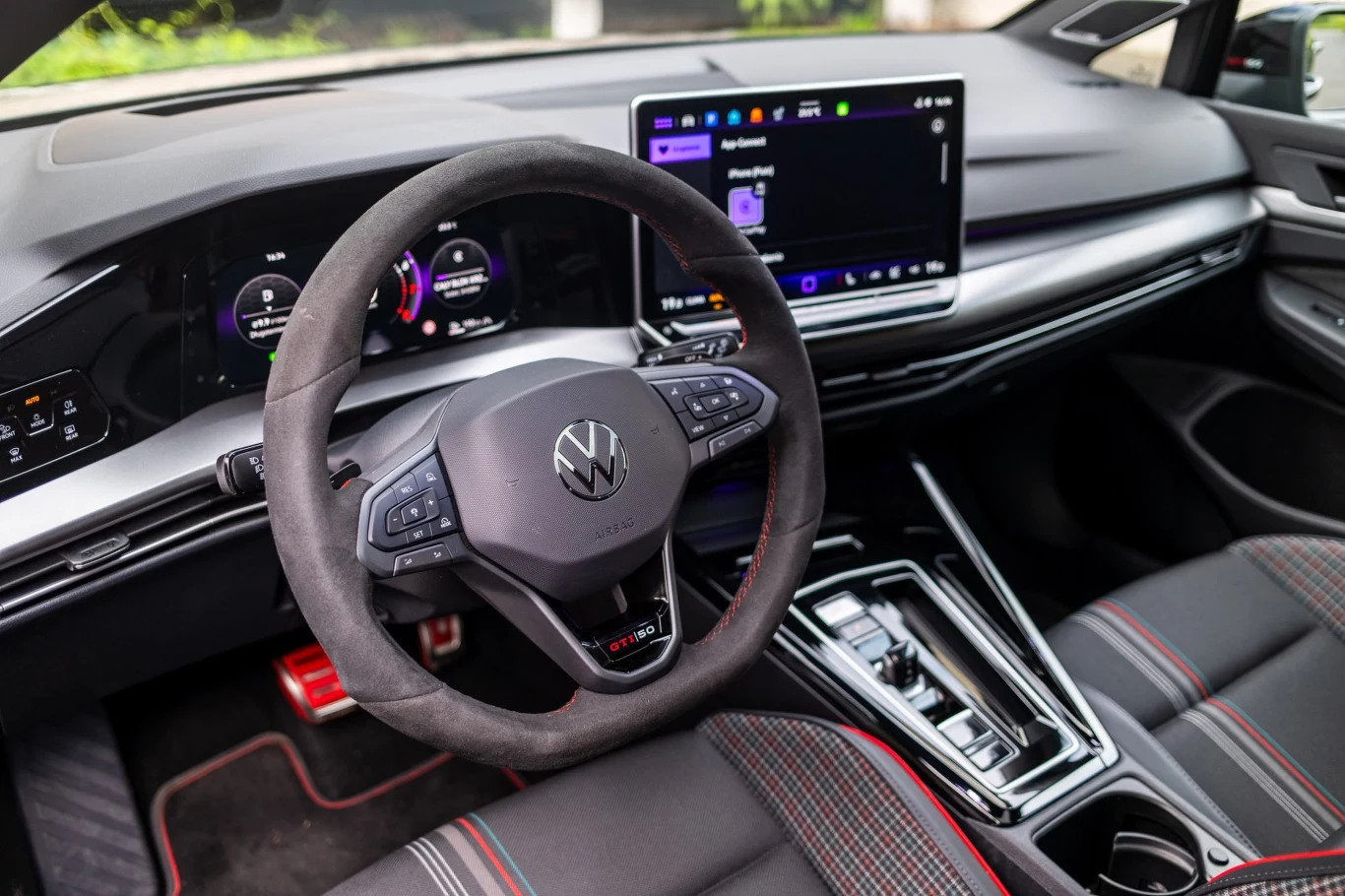 Kierownica z logo Volkswagen, nowoczesny cyfrowy kokpit z dużym ekranem dotykowym oraz sportowe fotele z kontrastującymi przeszyciami.