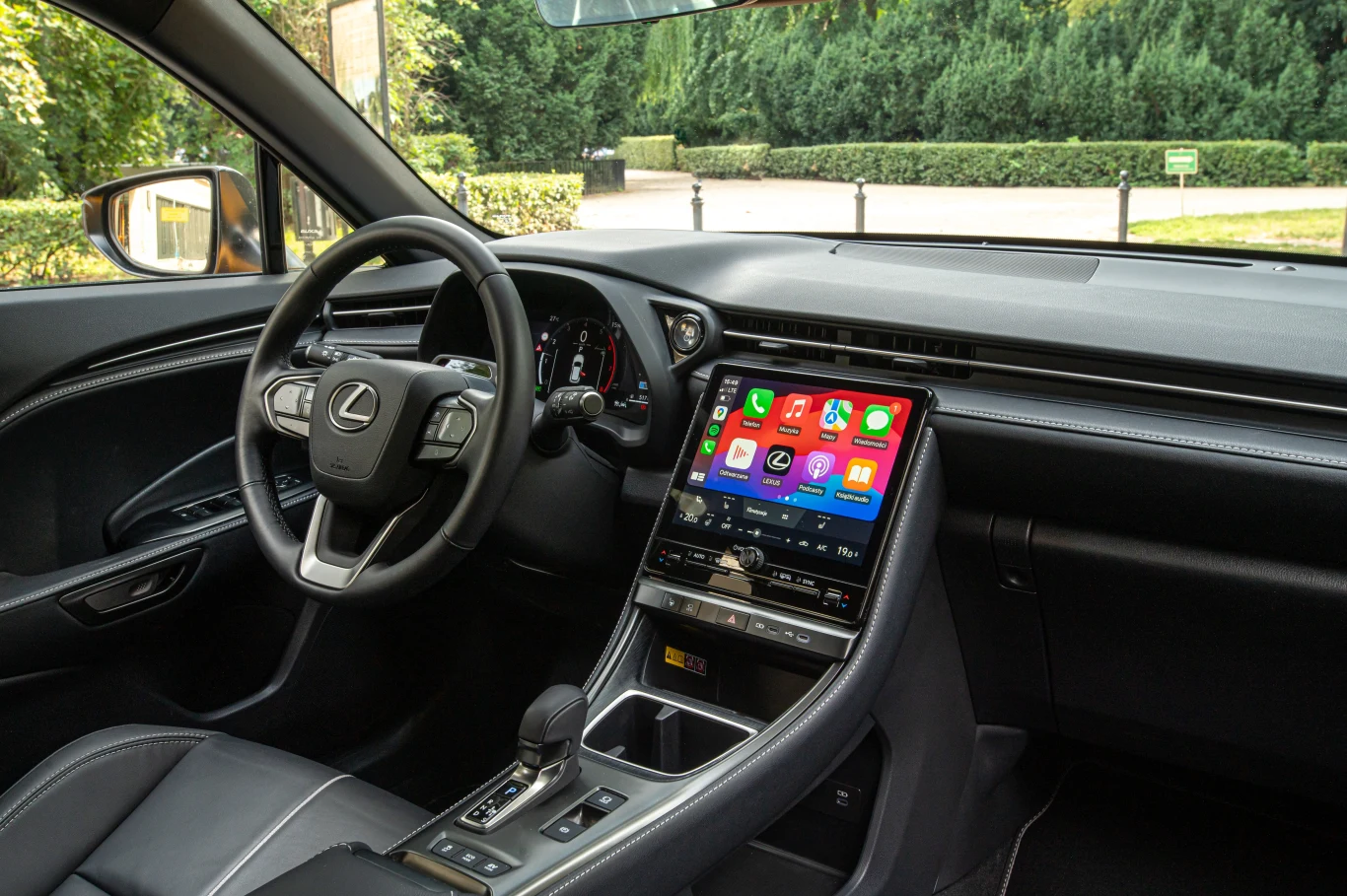 Nowoczesne wnętrze samochodu Lexus z dużym dotykowym ekranem systemu multimedialnego, skórzaną tapicerką oraz elegancką deską rozdzielczą.