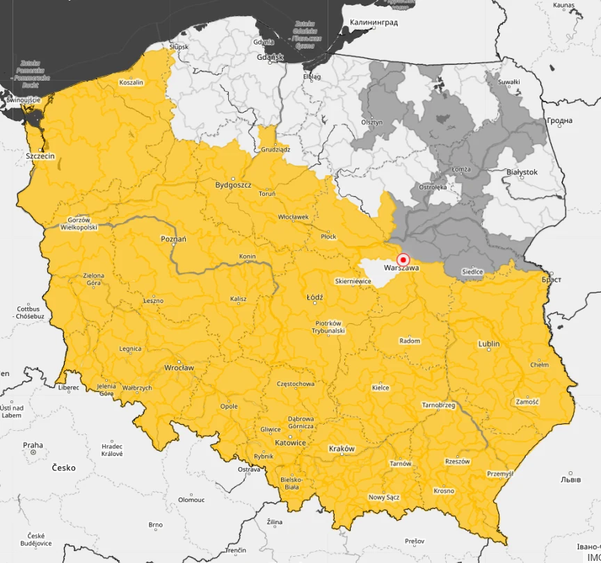 Mapa Polski z wyraźnie zaznaczoną strefą w kolorze żółtym obejmującą większość kraju oraz fragmentami terytorium pokrytymi kolorem szarym, wskazującymi na odmienne obszary; Warszawa oznaczona czerwoną pinezką.