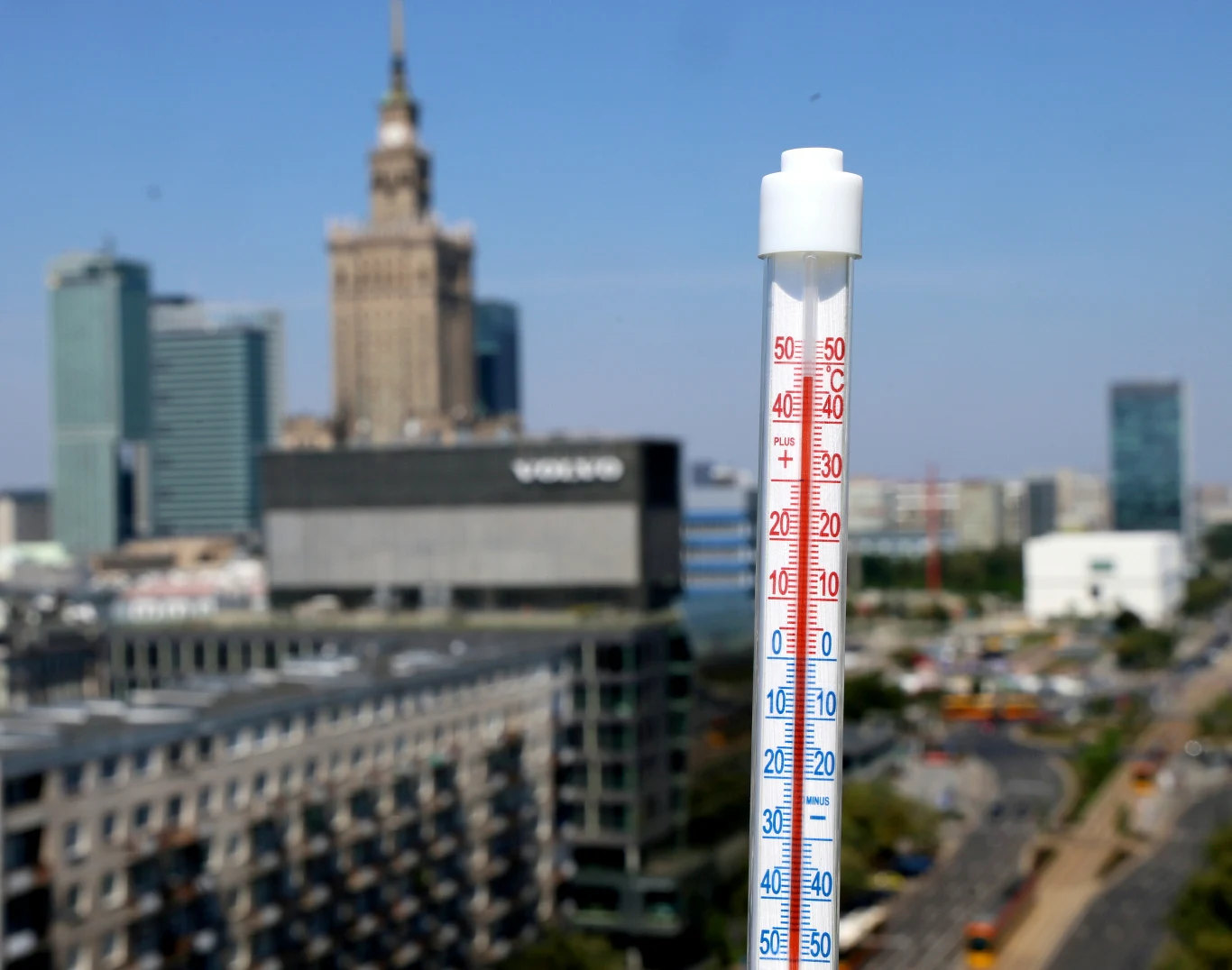 Zmiany klimatu i rosnące temperatury uderzają w polską gospodarkę. Brak działań może kosztować więcej Termometr wskazujący wysoką temperaturę na tle centrum Warszawy z Pałacem Kultury i nowoczesnymi biurowcami.