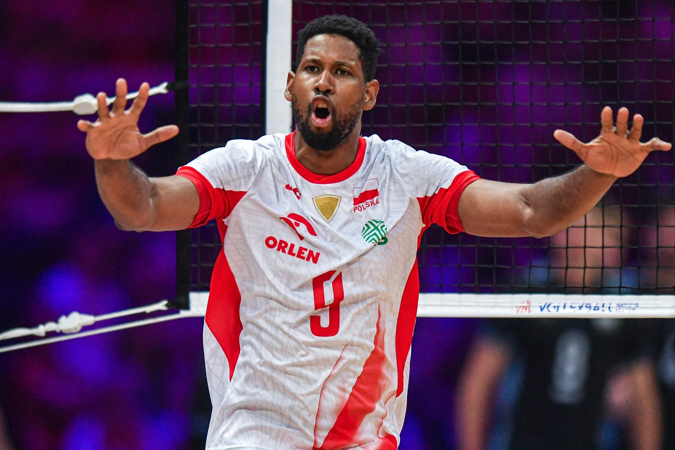 Wilfredo Leon w kadrze znów prezentuje się znakomicie Wilfredo Leon w biało-czerwonym stroju reprezentacji Polski z rozłożonymi rękami przy siatce podczas meczu.