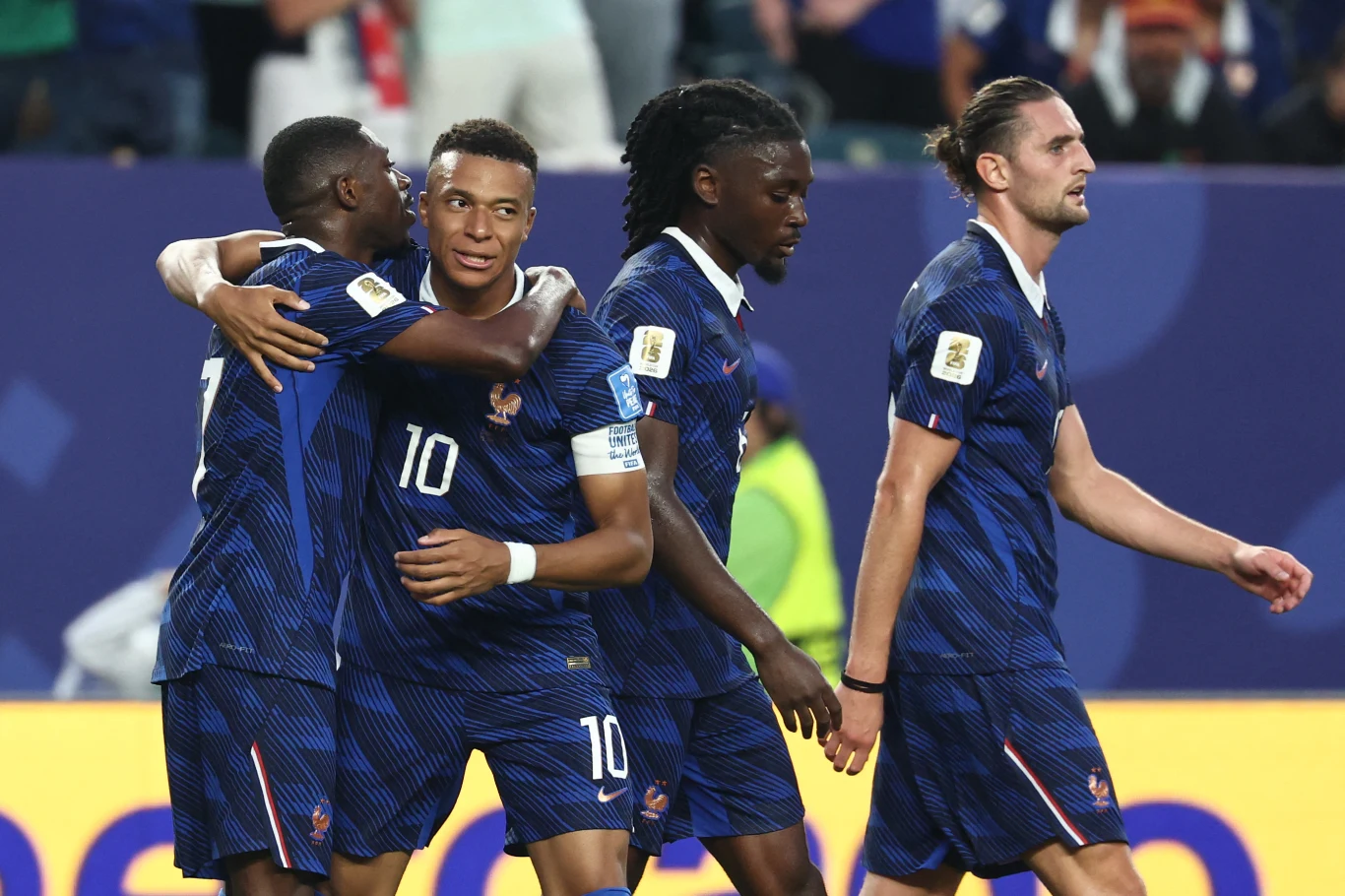 Ousmane Dembele, Kylian Mbappe, Manu Kone i Adrien Rabiot w barwach reprezentacji Francji Czterech piłkarzy w granatowych koszulkach z numerami świętuje zdobycie gola podczas meczu, dwóch z nich obejmuje się, a pozostali idą obok siebie na tle trybun stadionu.