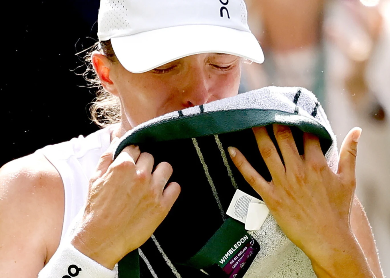 Wimbledon 2026. Iga Świątek po meczu z Taylor Townsend Iga Świątek w białej czapce, pochyla głowę i przykłada do twarzy ręcznik z logotypem Wimbledonu