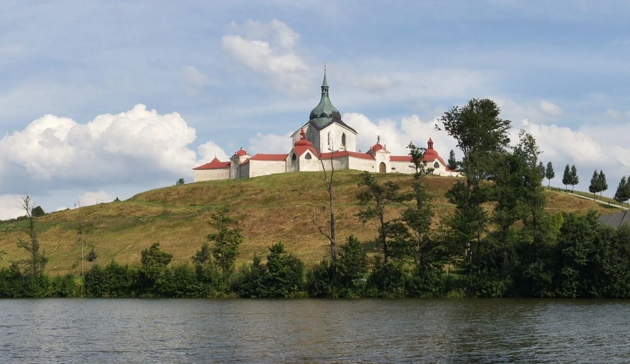 Sanktuarium św. Jana Nepomucena powstało na planie pięcioramiennej gwiazdy Barokowy kościół z charakterystyczną zieloną kopułą usytuowany na wzgórzu, otoczony zabudowaniami klasztornymi i murami, na pierwszym planie rzeka oraz zieleń drzew.
