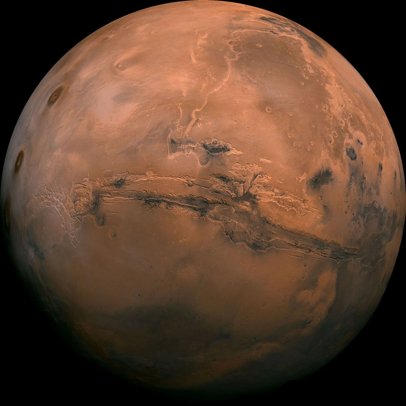 Valles Marineris to największy kanion w całym Układzie Słonecznym. Powierzchnia Marsa z wyraźnie widocznym kanionem Valles Marineris przecinającym planetę w poziomie oraz charakterystycznymi czerwonawo-brązowymi barwami i delikatnymi kraterami.