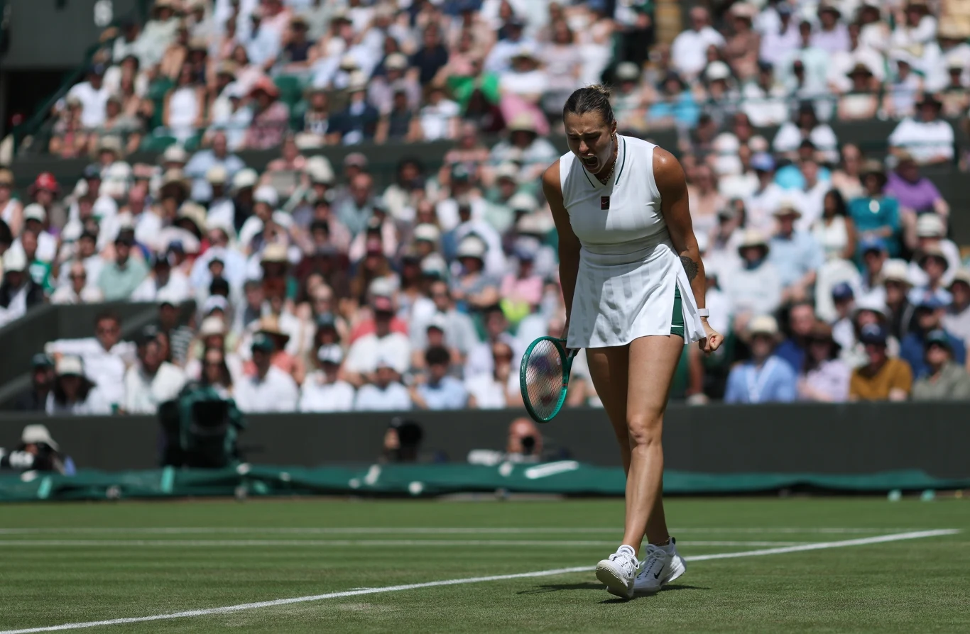 Aryna Sabalenka w meczu z McCartney Kessler Tenisistka w białym stroju na trawiastym korcie trzymająca rakietę, wyrażająca emocje podczas meczu przed liczną publicznością.