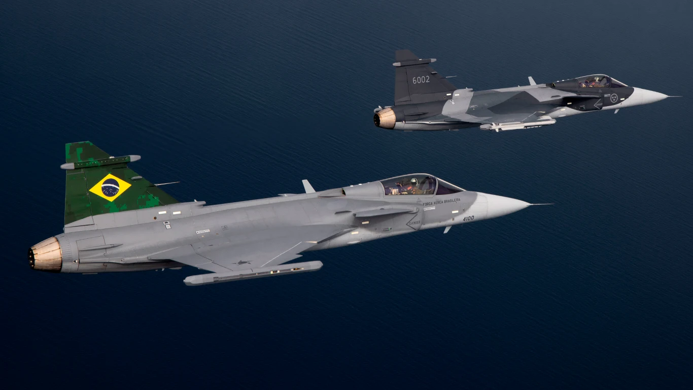 Dwa myśliwce wojskowe Saab Gripen lecące w formacji, jeden z nich z wyraźnym godłem Brazylii na stateczniku pionowym.