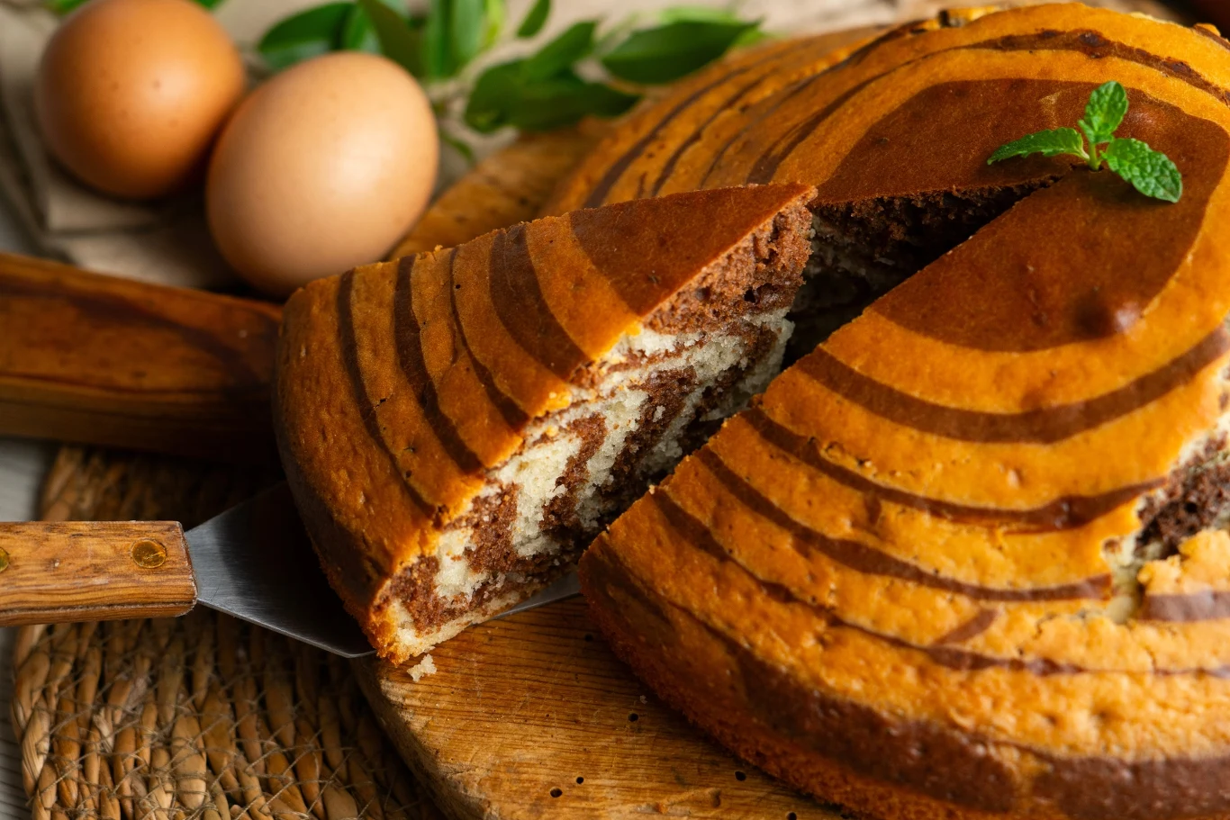 To ciasto robię, gdy nie mam czasu. Wychodzi wilgotne i miękkie za każdym razem Wilgotne ciasto kakaowo-waniliowe podane na drewnianym talerzu przed polaniem polewą czekoladową.