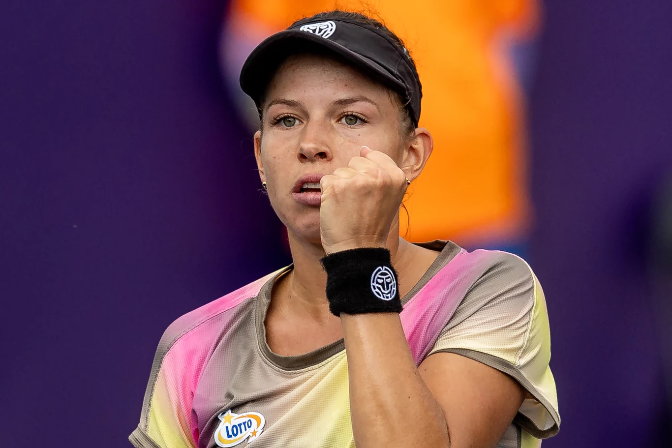 Tenisistka ubrana w sportową koszulkę i czapkę z daszkiem pokazuje zaciśniętą pięść, podkreślając silne emocje po rozegranej akcji na korcie.