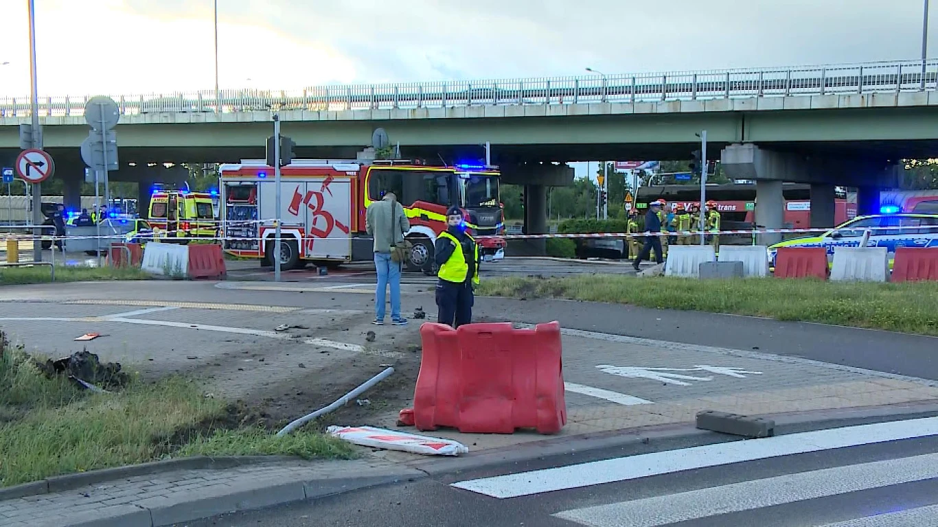 służby ratownicze oraz policja zabezpieczające miejsce wypadku drogowego w pobliżu wiaduktu, obecność wozu strażackiego i rozstawionych barier ochronnych