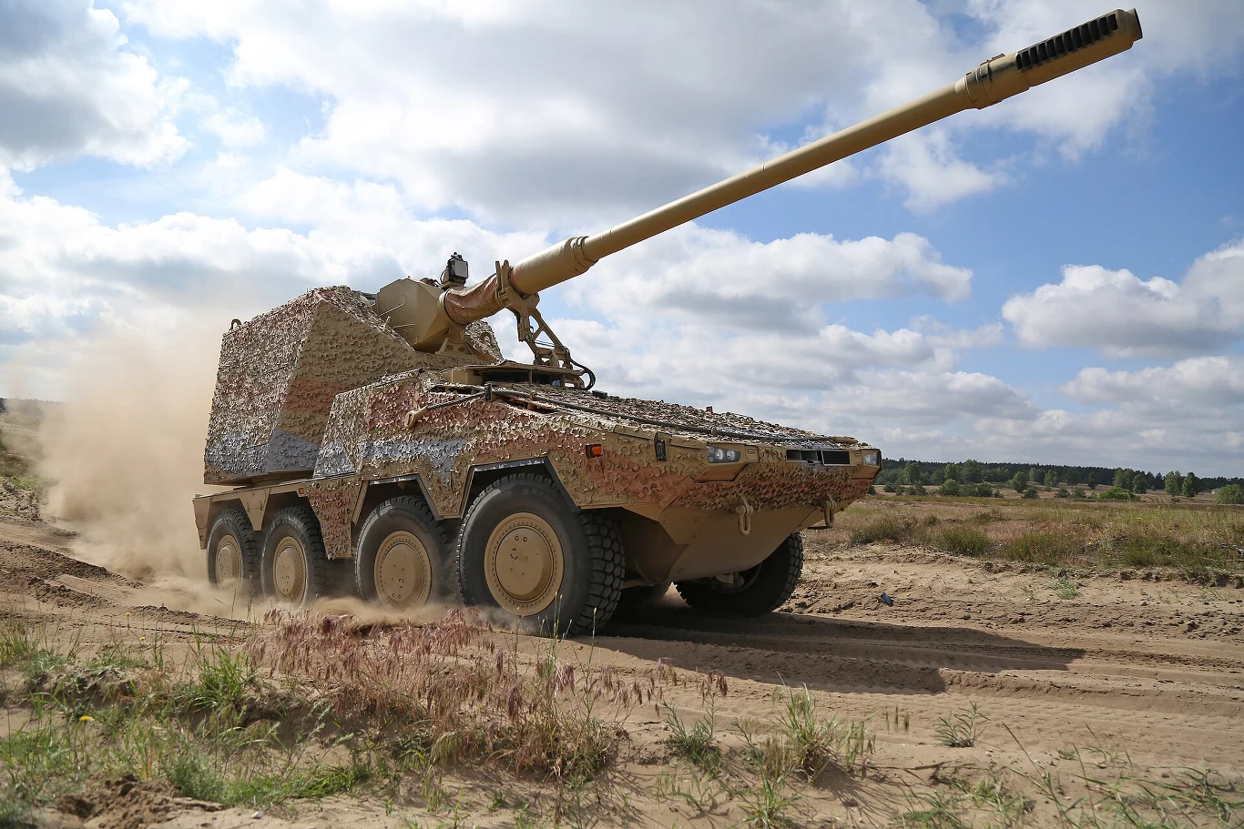 RCH 155 podczas testów. Opancerzone działo samobieżne na ośmiokołowym podwoziu poruszające się po piaszczystym terenie, z długą lufą skierowaną lekko ku górze i zamaskowaną siatką maskującą.