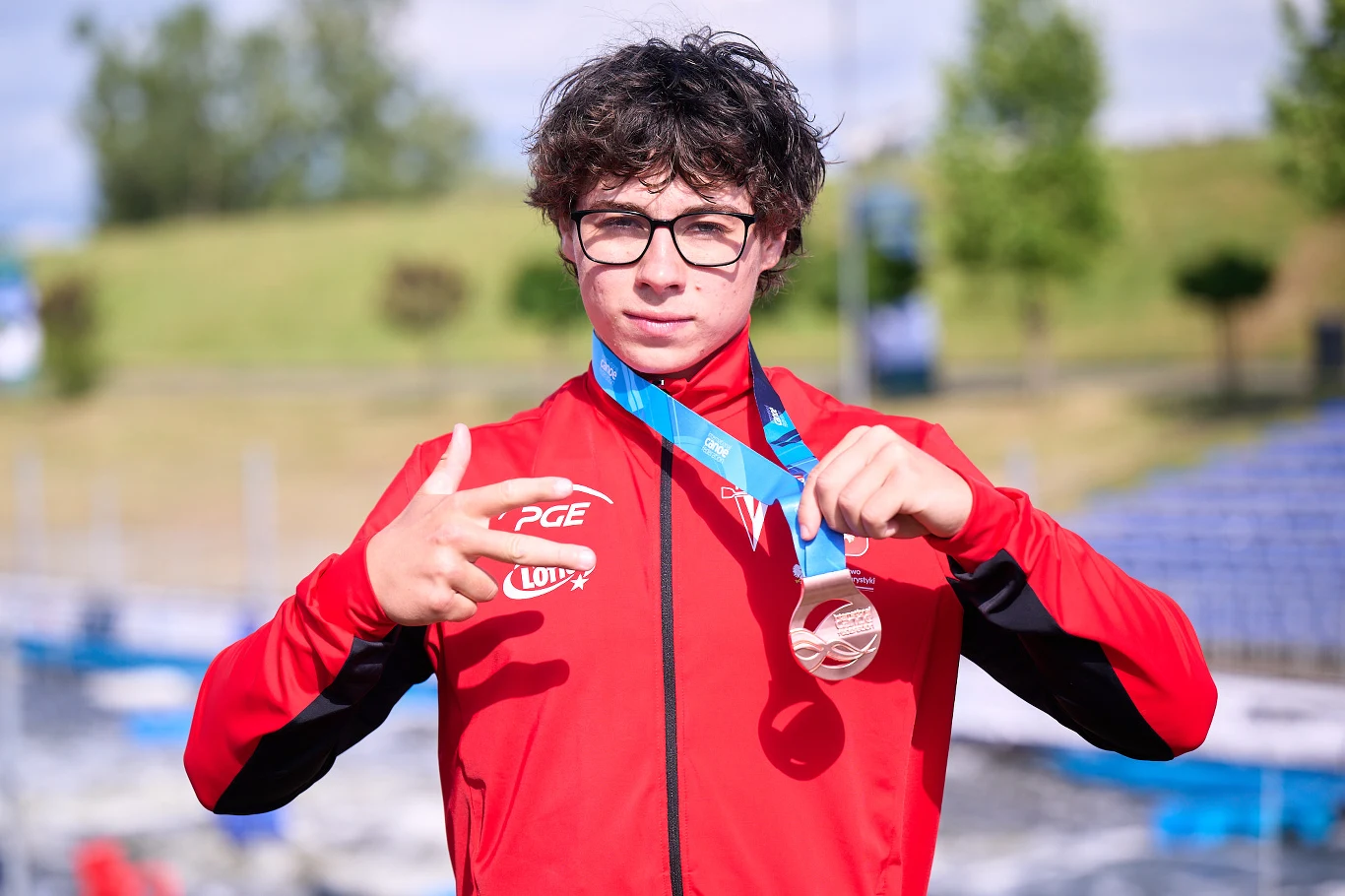 Marek Kulczycki Marek Kulczycki w czerwonym dresie PGE i LOTTO prezentuje srebrny medal na tle zieleni i trybun stadionu