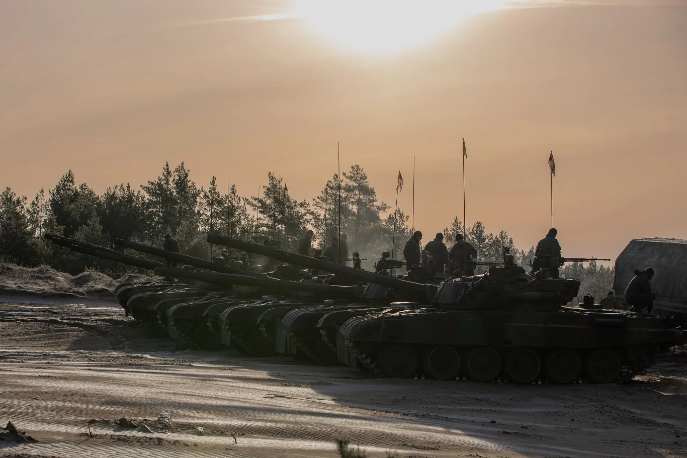 Polska przekazała Ukrainie m.in. czołgi podstawowe PT-91 Twardy (zdj. ilustracyjne) Szereg czołgów PT-91 Twardy na zaśnieżonym placu, żołnierze na pojazdach, w tle drzewa i zachód słońca.