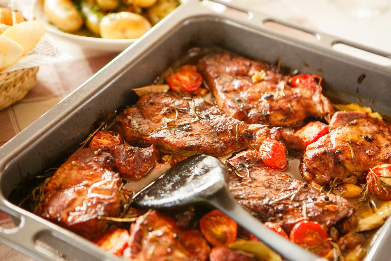 Karkówka w pomidorach Kawałki karkówki pieczone w pomidorach i przyprawach, podane w blaszce obok gotowanych ziemniaków.