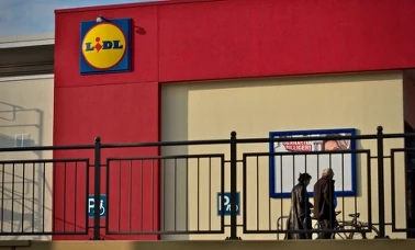 Wejście do sklepu Lidl z logo sieci i klientami przed sklepem 