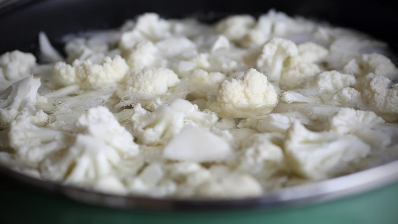 Details of a cauliflower in a saucepan of boiling water for cooking. Różyczki kalafiora w garnku z gotującą się wodą, przygotowywane do gotowania.
