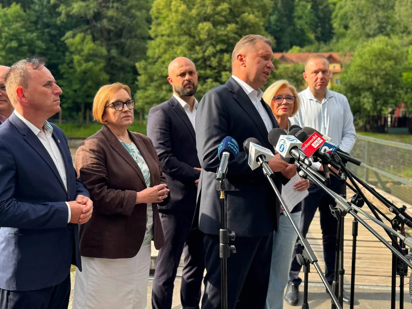 PiS chce wyjaśnień ws. katastrofy ekologicznej przy zaporze Pilchowice Sześć osób z PiS przy mikrofonach na zewnątrz, w tle drzewa i budynki, konferencja ws. zapory Pilchowice.