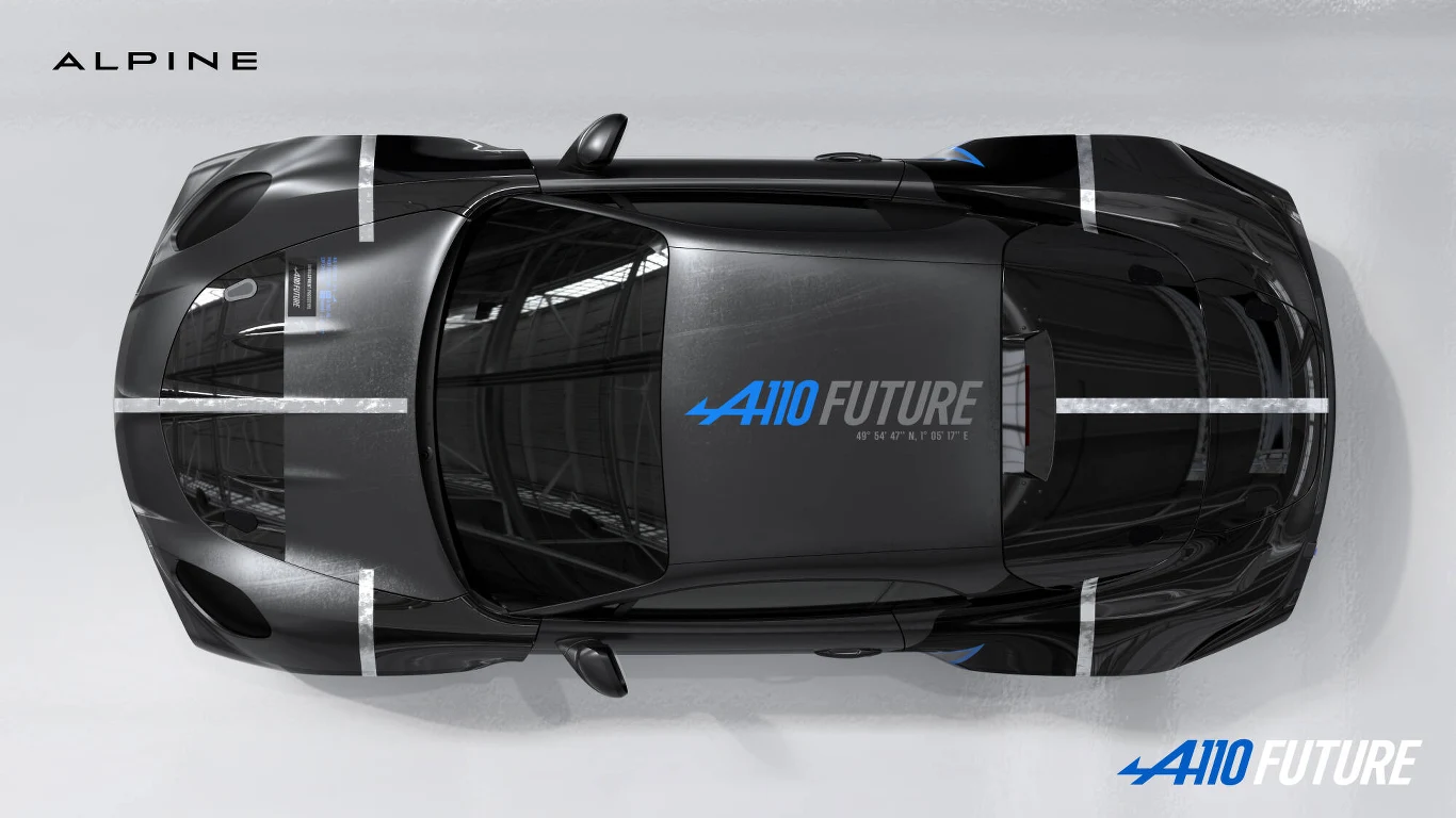 Czarny samochód sportowy Alpine A110 Future z charakterystycznymi białymi pasami biegnącymi wzdłuż i wszerz karoserii, widok z góry na opływową sylwetkę pojazdu i wyraźne oznaczenia modelu na masce i przy tylnej osi.