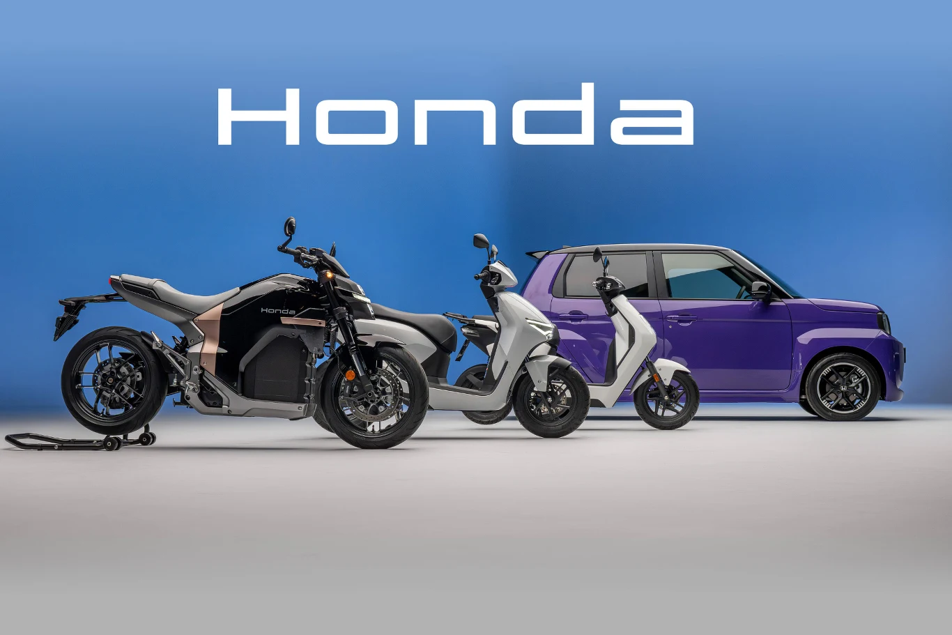 Elektryczny motocykl, skuter oraz kompaktowy samochód ustawione w jednym rzędzie na jasnym tle, w tle duży biały napis Honda.