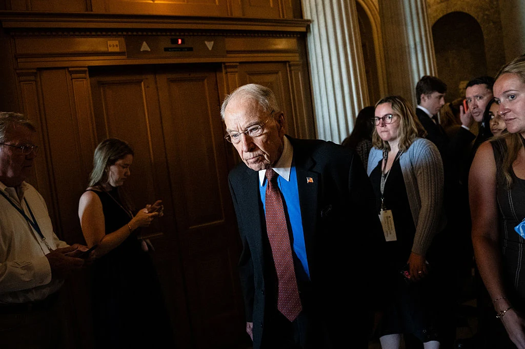 Przewodniczącym pro tempore Senatu jest 92-letni Chuck Grassley z Iowy. Starszy mężczyzna w garniturze i czerwonym krawacie idący przez elegancki, drewniany korytarz, w otoczeniu kilku osób zwracających na niego uwagę.