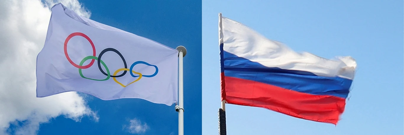 Dwie powiewające na wietrze flagi: biała flaga z pięcioma kolorowymi olimpijskimi kołami oraz flaga Rosji w barwach białej, niebieskiej i czerwonej na tle nieba.