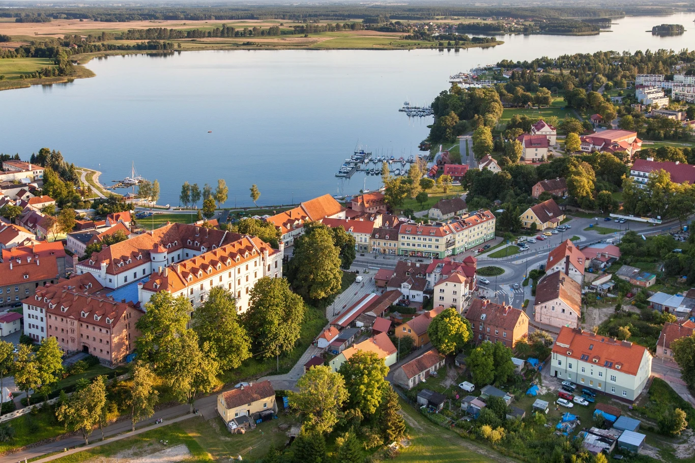 Zabudowania małego miasta położone nad rozległym jeziorem z mariną, otoczone licznymi drzewami i zielenią.