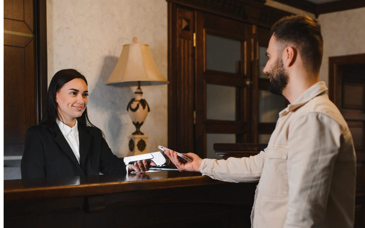 Hotele, w których nocleg sam w sobie jest atrakcją Recepcjonistka w eleganckim stroju odbiera dokument od mężczyzny stojącego po drugiej stronie recepcji.