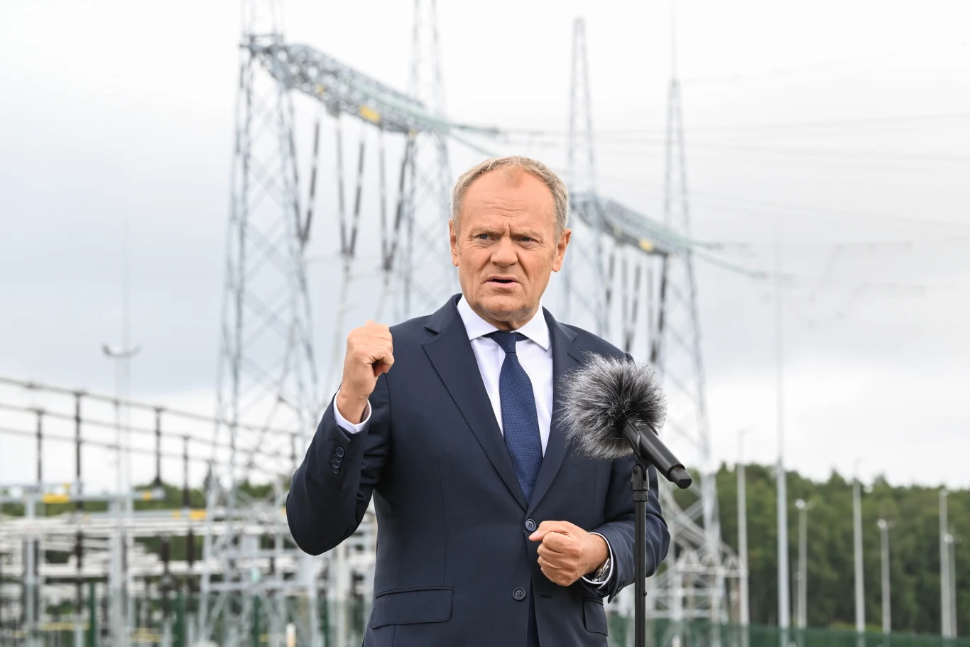 Premier Donald Tusk podczas uroczystego zakończenia budowy Stacji 400 kV Choczewo Premier Donald Tusk przemawia przy mikrofonie, w tle widać stację elektroenergetyczną w Choczewie.