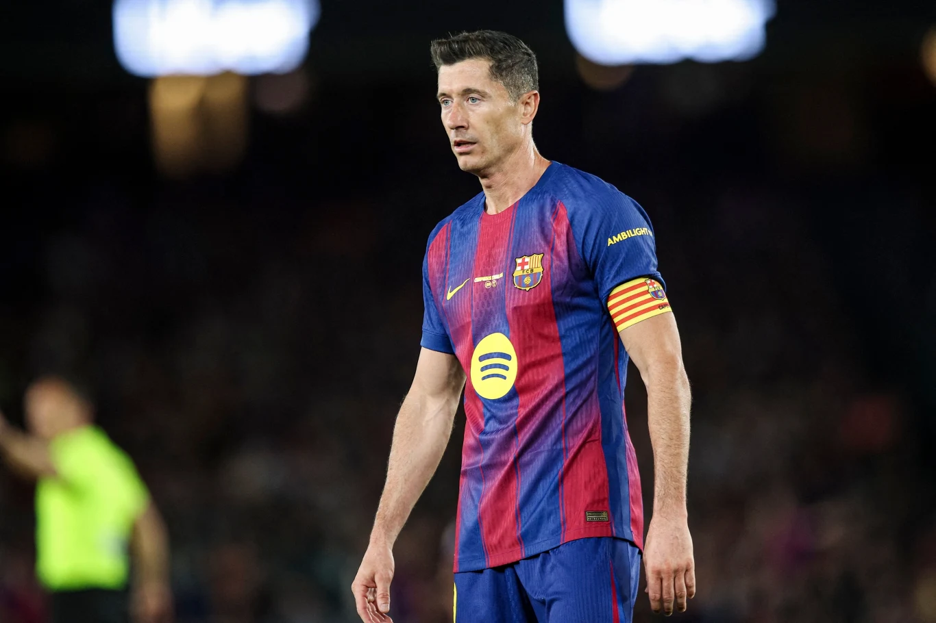 Piłkarz FC Barcelony w granatowo-bordowym stroju z żółtą opaską kapitana stoi na murawie stadionu podczas meczu.