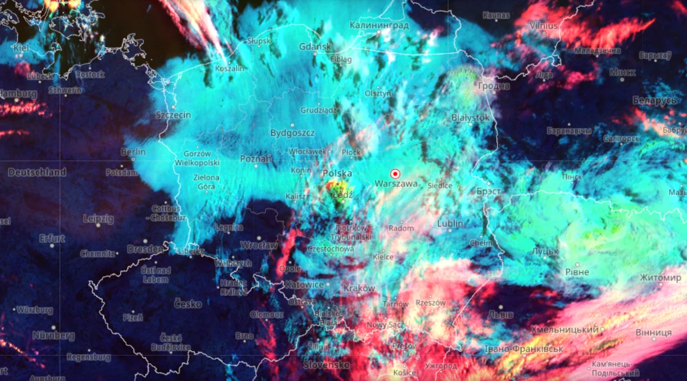 Kolorowa mapa satelitarna pokazująca intensywne zachmurzenie nad Polską z wyraźnymi pasmami chmur oraz zaznaczonym punktem Warszawy pośród silnych opadów.