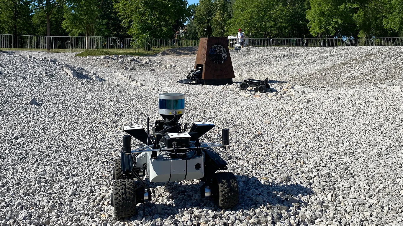 Polski tor marsjański powiększony. Odzwierciedla obszar Czerwonej Planety. Robot mobilny z czujnikiem laserowym na żwirowym polu testowym MARS, w tle stalowa konstrukcja i drugi robot.