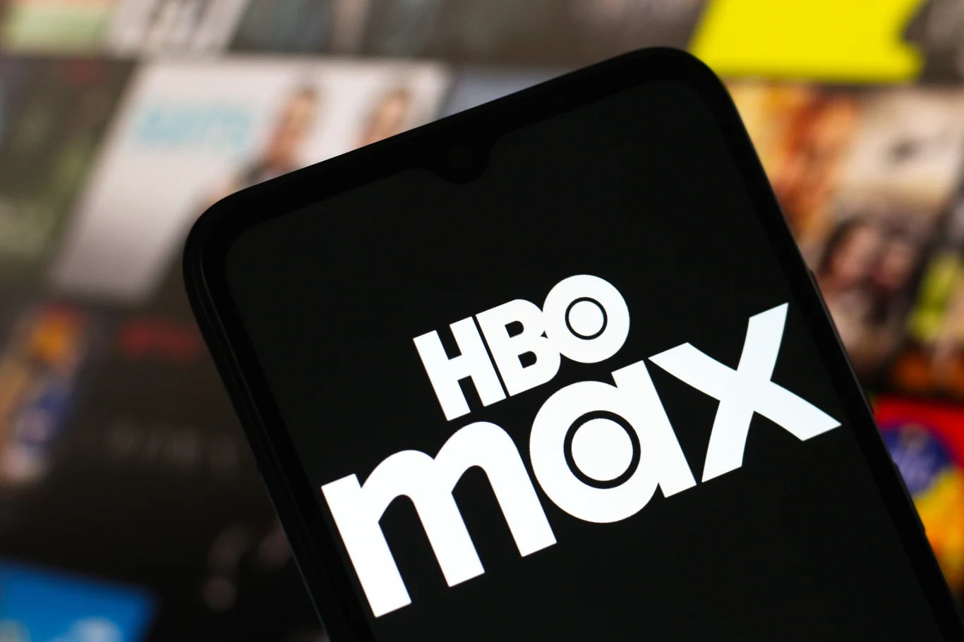 Co oglądać na HBO Max? Logo platformy HBO Max na ekranie smartfona, w tle rozmyte miniaturki filmów i seriali.