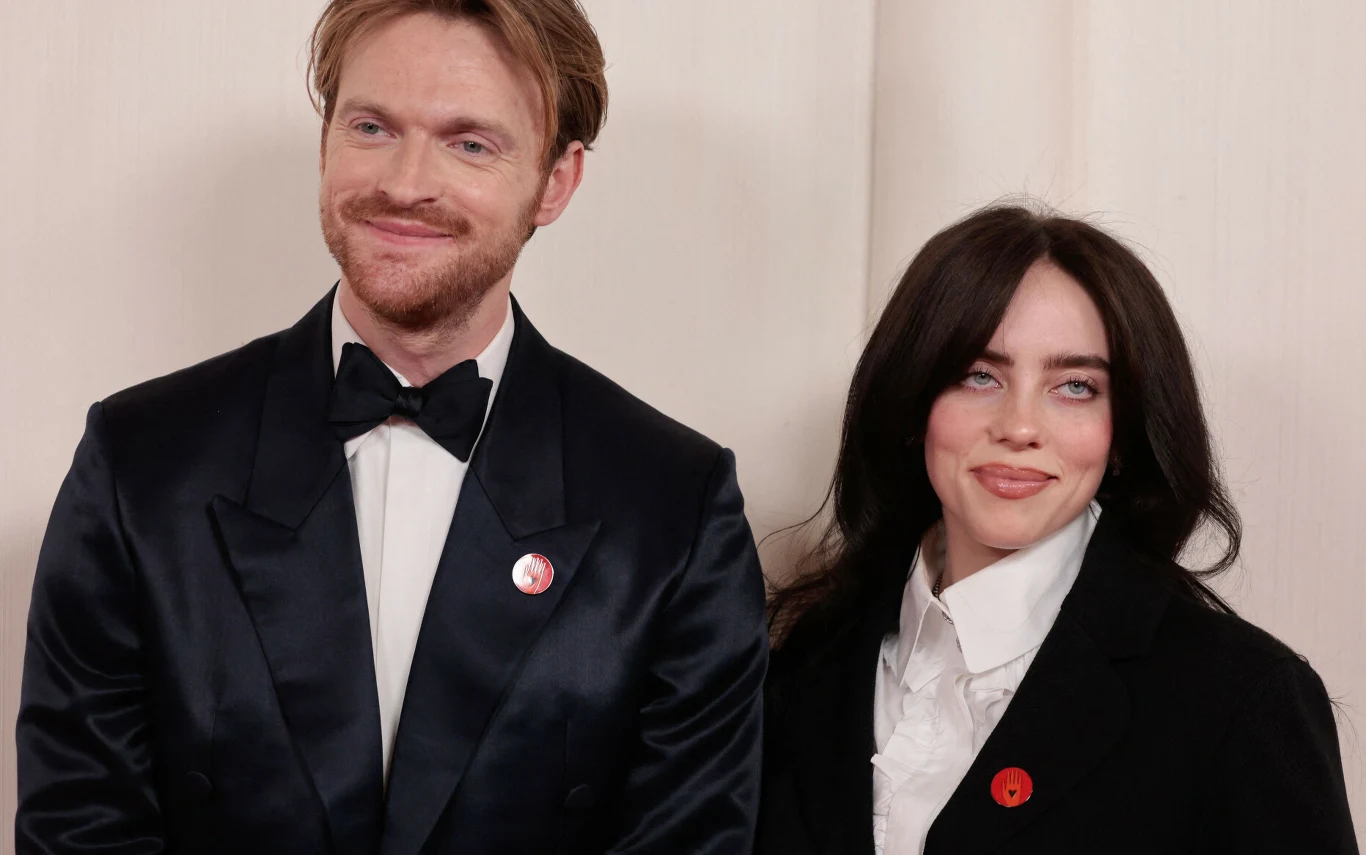 Finneas O'Connell i Billie Eilish. Finneas O'Connell i jego siostra wokalistka Billie Eilish stoją obok siebie, uśmiechają się na wydarzeniu branżowym.