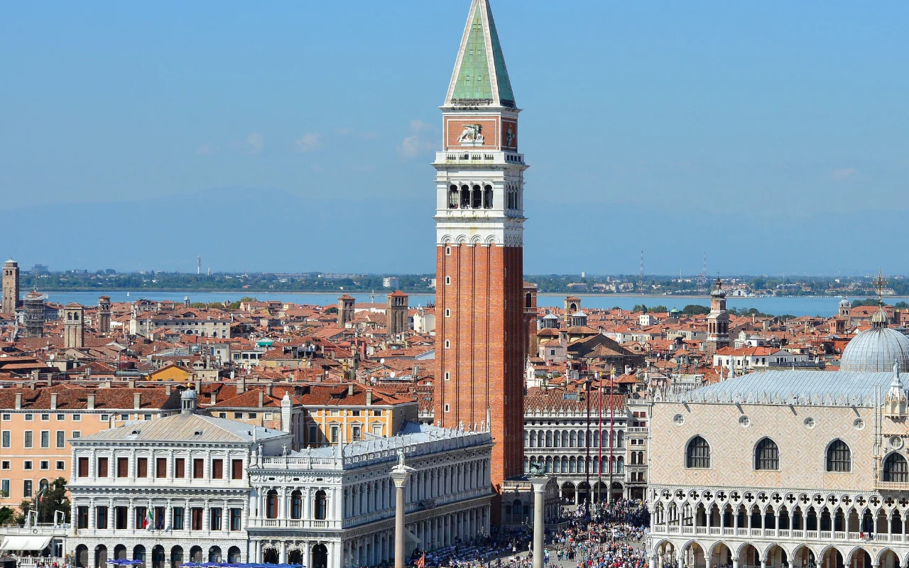 Campanile di San Marco w Wenecji Dominująca na tle miasta dzwonnica świętego Marka, otoczona zabytkowymi budynkami Wenecji, z widokiem na lagunę.