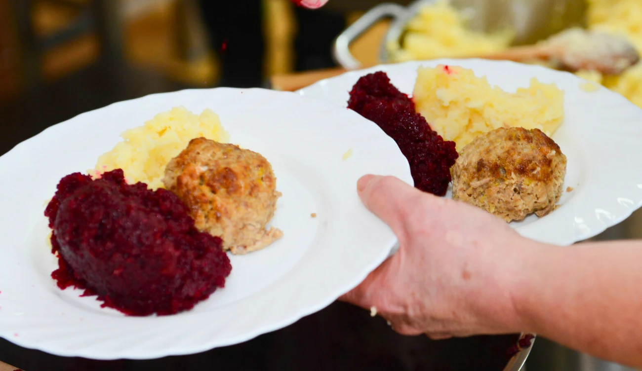 Rewolucja w szkolnych stołówkach od 1 września Dwa talerze z mielonym kotletem, ziemniakami puree i buraczkami w rękach osoby, szkolna stołówka.