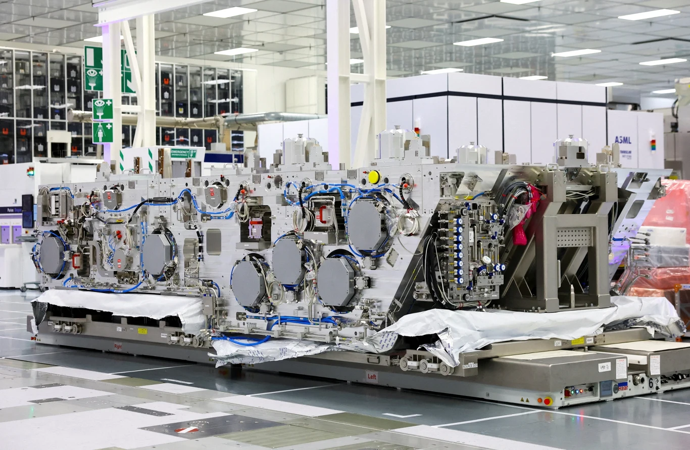 Dolny moduł maszyny High NA EUV firmy ASML w siedzibie belgijskiego instytutu badawczego IMEC Duża, zaawansowana technologicznie maszyna przemysłowa w nowoczesnej hali produkcyjnej, wyposażona w liczne panele, przewody i elementy elektroniczne rozmieszczone symetrycznie na jej powierzchni.