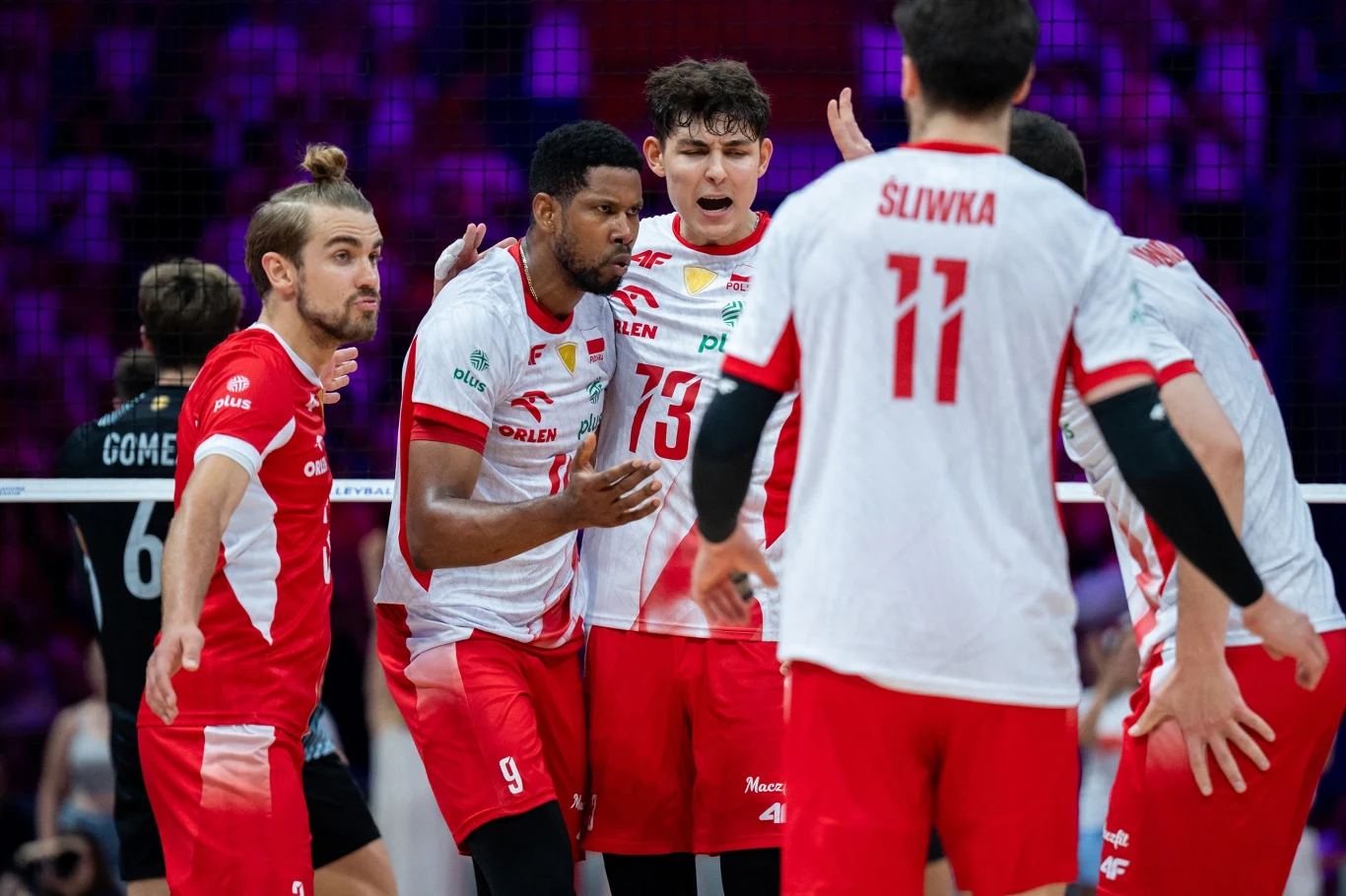Grupa siatkarzy w biało-czerwonych strojach świętuje zdobycie punktu na boisku podczas meczu.