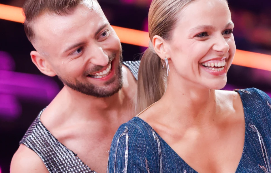 Vanessa Aleksander i Michał Bartkiewicz Uśmiechnięta para w wieczorowych strojach na tle kolorowych świateł.