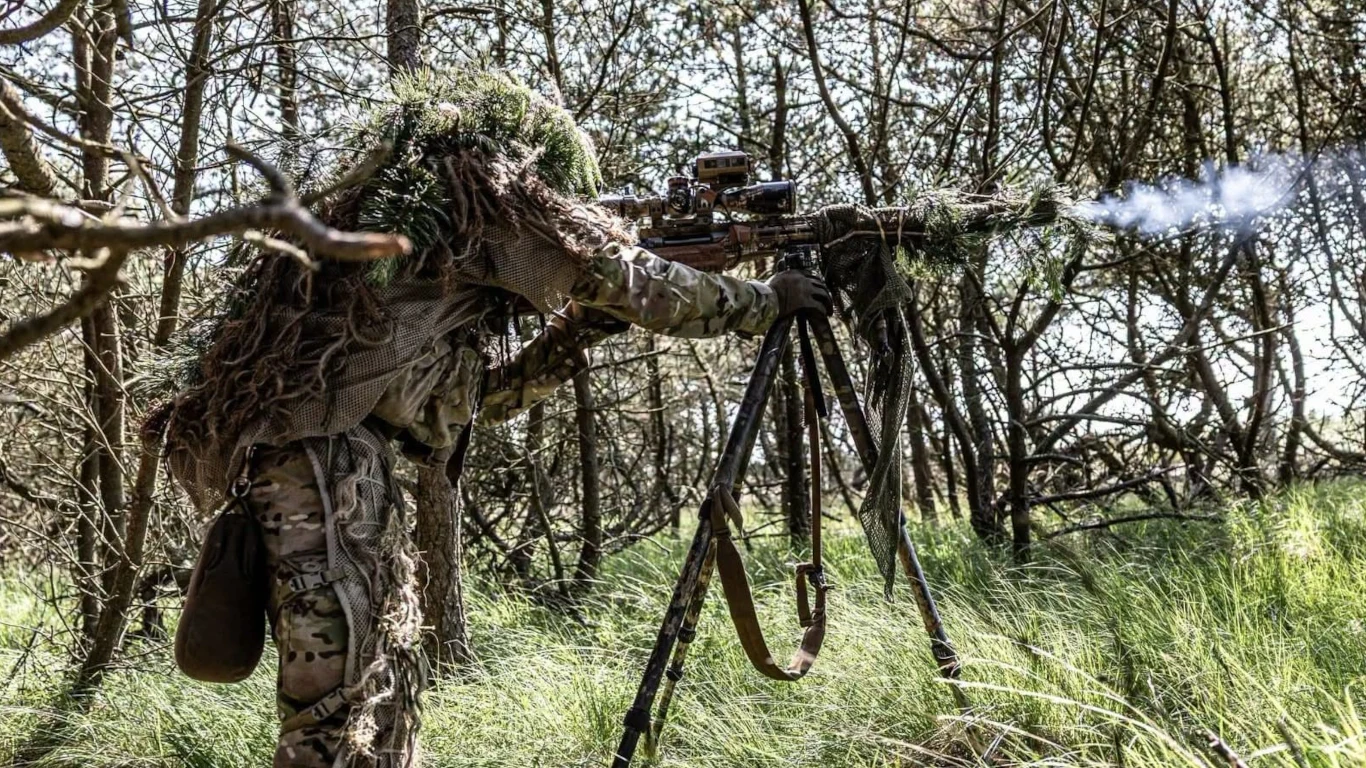 Polscy strzelcy wyborowi rywalizowali na prestiżowych zawodach Danish International Sniper Competition. Mierzyli się z żołnierzami z 12 państw. Polski snajper w kamuflażu ghillie oddaje strzał z karabinu na statywie wśród drzew podczas zawodów w Danii.